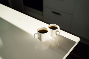 two cups of coffee with a hot, aromatic drink. There are two servings of Americano and espresso on the table. Morning light from the window