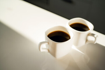 two cups of coffee with a hot, aromatic drink. There are two servings of Americano and espresso on the table.