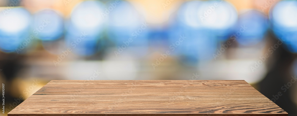 Poster empty wood table with blur people in coffee shop background bokeh light and leaf foreground,mockup f