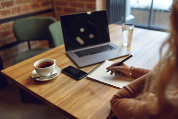 Woman taking notes while working at cafe