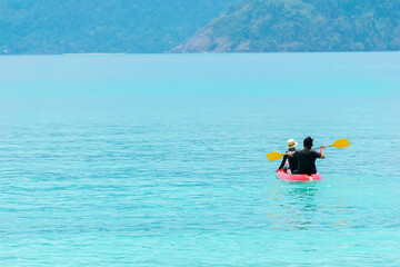 A couple helping canoe in a clear morning sea. Blue green sea