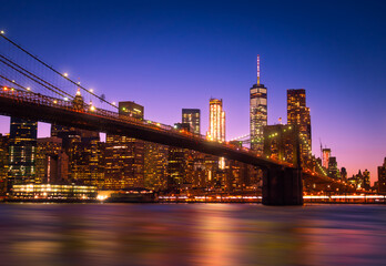 Obraz na płótnie Canvas View of Brooklyn Bridge and Manhattan skyline WTC Freedom Tower from Dumbo by night, Brooklyn. Brooklyn Bridge is one of the oldest suspension bridges in the USA