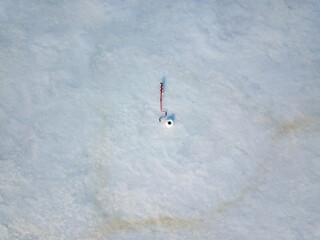 Manual ice screw on the ice near the hole. Aerial drone view. Winter sunny morning.