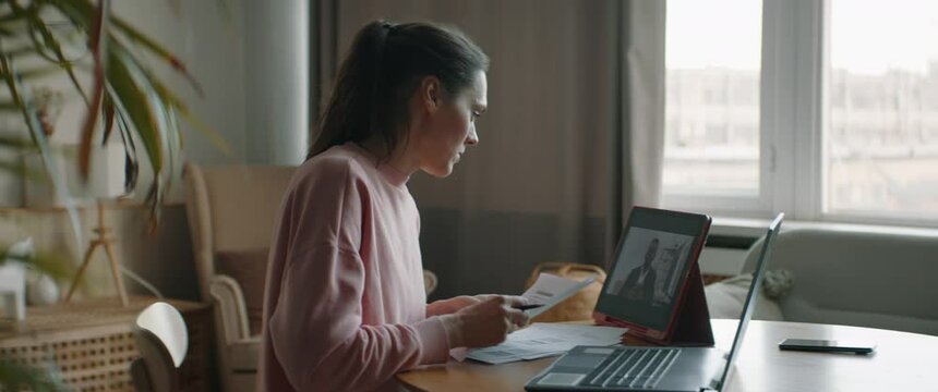 DOLLY IN Mid 30s Caucasian female working from home, having a video call with client or colleague. WFH, stay home, COVID-19 coronavirus pandemic new normal concept