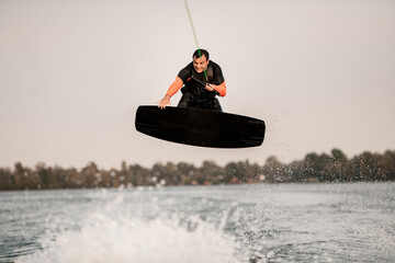 Fototapeta na wymiar adult man wakeboarding on river and jumping on splashing wave