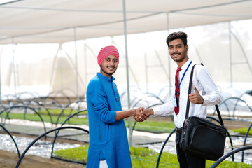 Fototapeta premium Young indian agronomist with farmer at greenhouse