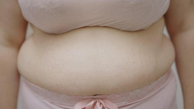 Obese female touching waist fat, lack of physical activity, unhealthy nutrition