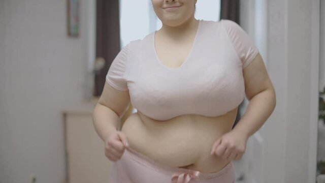 Smiling plus size woman with belly fat dancing, body positive, inner confidence