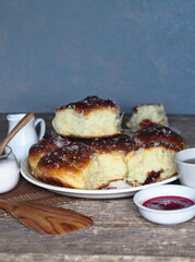Homemade cake.Buns filled with jam, sprinkled with sesame and icing sugar, on an ancient wooden table, with ingredients and a Cup of tea, with a gray background.