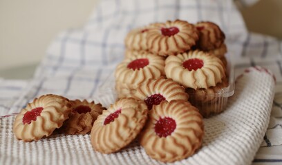 sand cookies with jam in the middle on a napkin and in a plastic box