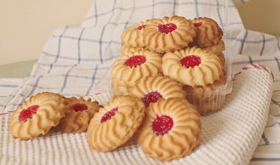sand cookies with jam in the middle on a napkin and in a plastic box