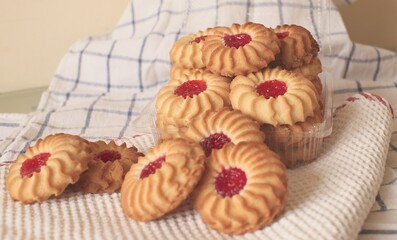 sand cookies with jam in the middle on a napkin and in a plastic box