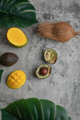 Sliced tropical fruit mango, coconut and broken avocado on marble surface