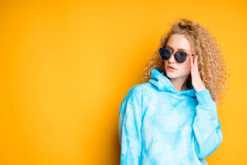 Fototapeta premium A young girl in glasses with curly hair looks to the side. Bright colors