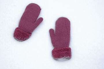 Warm mittens in the snow. Two mittens lie on white snow top view. Cold season, snowy winter.