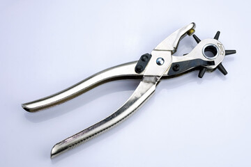 Metal hole punch for punching holes in leather goods. Device for punching holes in the sewing industry. Puncher with different attachments on a white background.