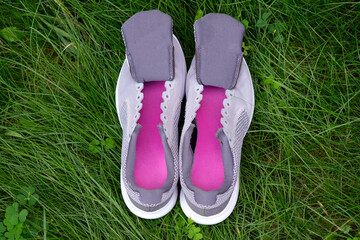 Gray sneakers with tongues top view. Women's sneakers without laces with crimson insoles on a background of green grass. Washing your sneakers after running.