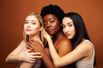 Obraz premium young pretty asian, caucasian, afro woman posing cheerful together on brown background, lifestyle diverse nationality people concept
