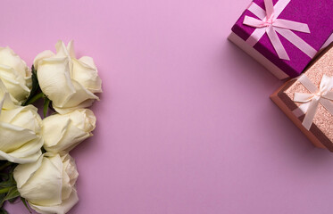 Postcard. White roses and a gift box on a pink background. Congratulations on March 8, Valentine's Day, Mother's Day, Birthday, Anniversary, Wedding, Teacher's Day, to women. Copy space.Flatly