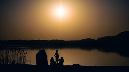 Family on the shore of a lake at sunset