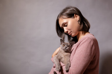 Young woman holding a gray cat in her arms