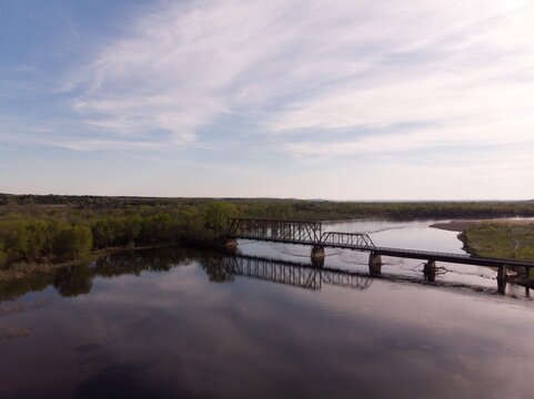 Wood And Steel Rail Road Bridge Over A Winding River As The Sun Sets