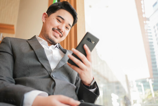 close up adult middle eastern businessman hold smartphone to checking stock market exchange or read news on online website at office room in relax time for lifestyle business concept