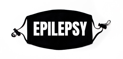 Black medical face mask on a light background with the inscription EPILEPSY. Disease prevention....