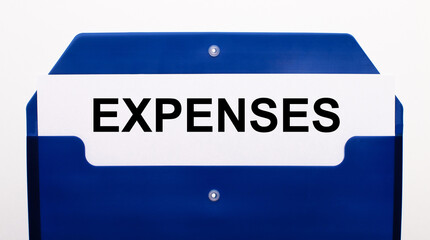 Fototapeta premium On a white background, a blue folder for papers. In the folder is a sheet of paper with the word EXPENSES