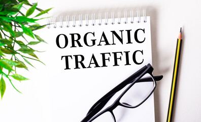 ORGANIC TRAFFIC is written in a white notebook next to a pencil, black-framed glasses and a green...
