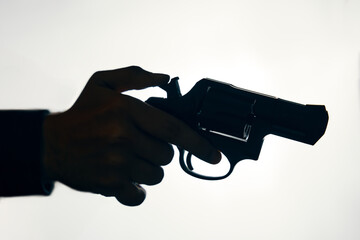 Silhouette of hand with revolver on white background. Man pulls the trigger of gun to fire. Criminal with pistol close up. Firearm for attack or defense.