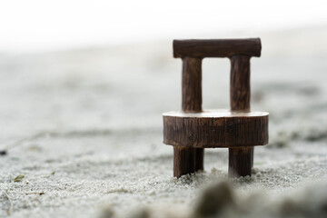 Wooden tiny chair macro shot on sand. brown chair on sand close up shot