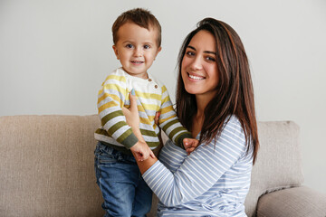 Young beautiful mother with her two year old son at home. Woman spending quality time with her toddler child. Close up, copy space, background