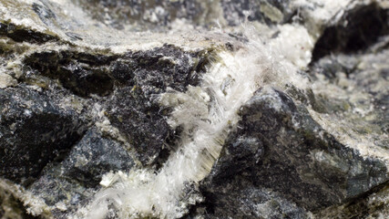 White fibers of asbestos mineral in stone, close-up.
