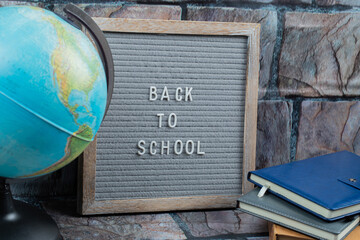 Obraz premium Back to school phrase embedded on grey tissue with a globe around