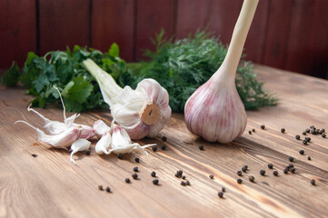 Garlic, spices and herbs on a wooden background.