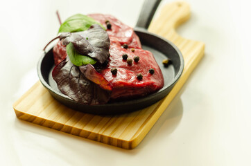 Raw beef fillet steak with spices on a small pan prepared for frying