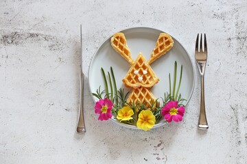 Waffles in the shape of an Easter bunny on a decorative meadow. Flat layot, copy space