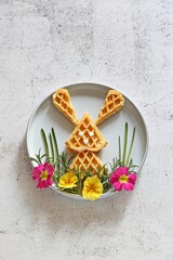 Waffles in the shape of an Easter bunny on a decorative meadow. Flat layot, copy space