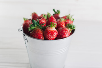 Juicy fresh strawberries in a metal bucket on a white background