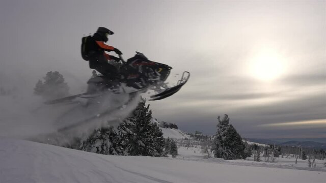 SLOW MO: video footage of jumping snowmobilers at sunset. the snowmobile flies through the air and creates large and beautiful swirls of snow. ProRes 422. HD 500fps