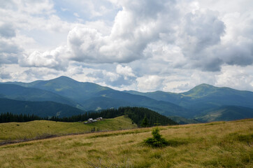 Mountain pasture with shepherd houses in high mountains. Chornohora ridge with mount Hoverla and Petros on background. Carpathians in summer, Ukraine