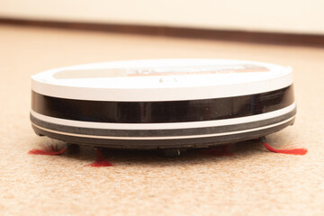 White robot vacuum cleaner cleans the floor. Automatic house cleaning