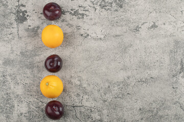 Set of fresh healthy plums with lemons on stone background