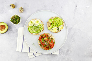 Three toasts with egg, avocado, micro greens, cucumbers and tomatoes. Healthy breakfast , plant based food. Top view.
