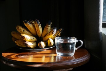 Banana and water for breakfast. Banana and water on the wooden table near the window.