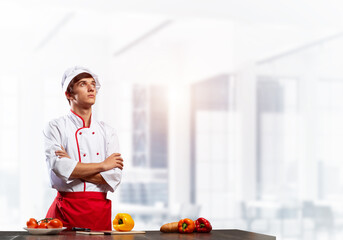 Young male chef standing with folded arms