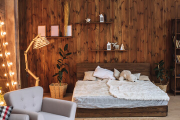 Bright interior of the bedroom with wooden wall, a wooden bed with white, loft interior