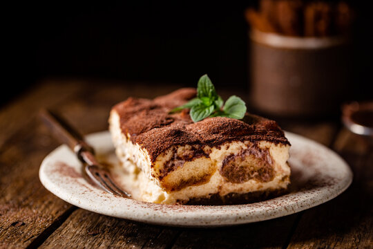 Piece of traditional Italian dessert tiramisu on dark background