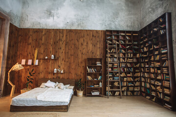 Bright interior of the bedroom with wooden wall, a wooden bed with white, loft interior with decorative lamp and book shelves